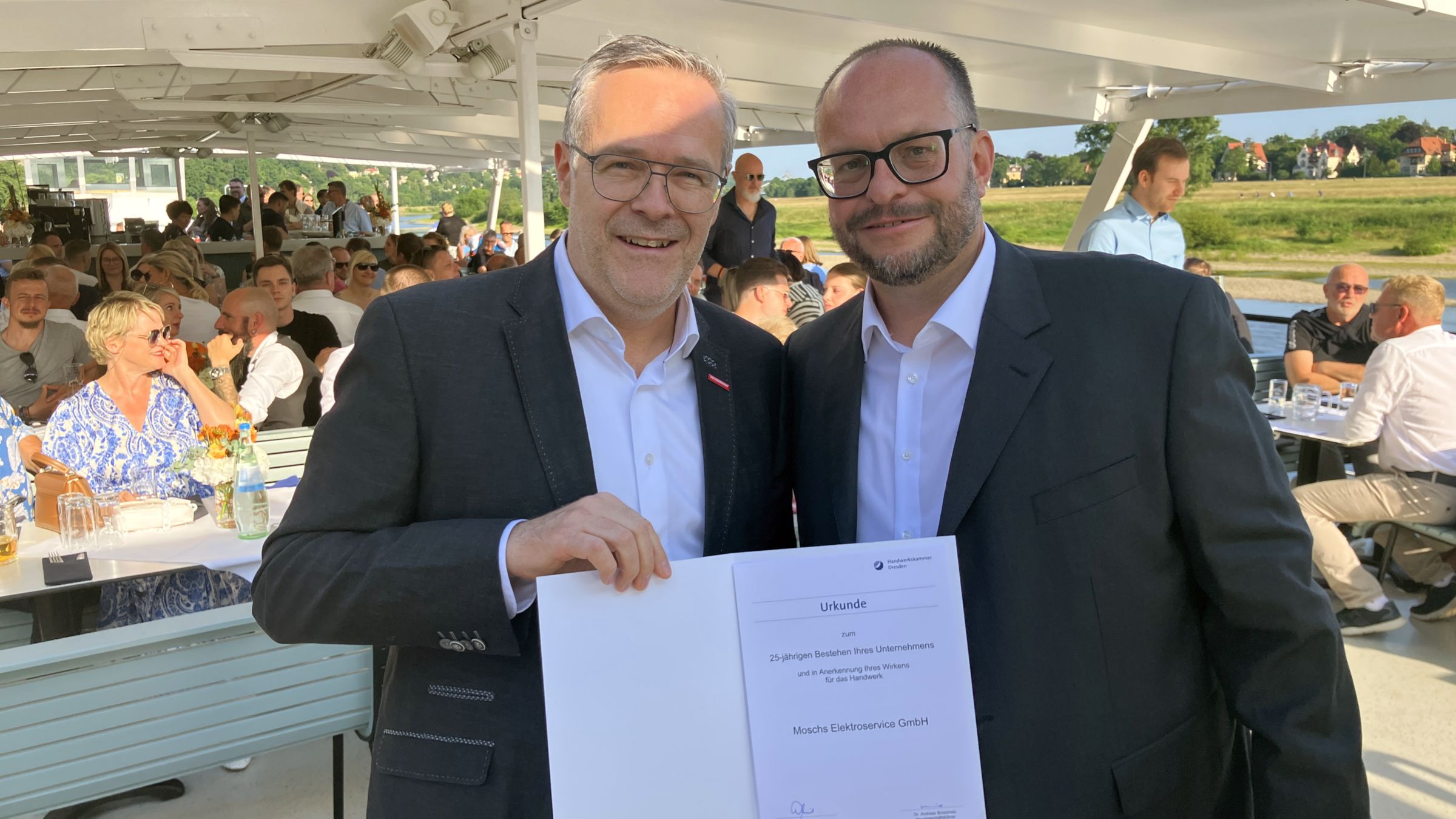 Jörg Dittrich, Präsident des Zentralverbands des Deutschen Handwerks und der Handwerkskammer Dresden (li.) überreicht die Urkunde zum 25-jährigen Geschäftsjubiläum der „Moschs Elektroservice GmbH“ an Geschäftsführer Alexander Mosch - Foto: meeco Communication Services