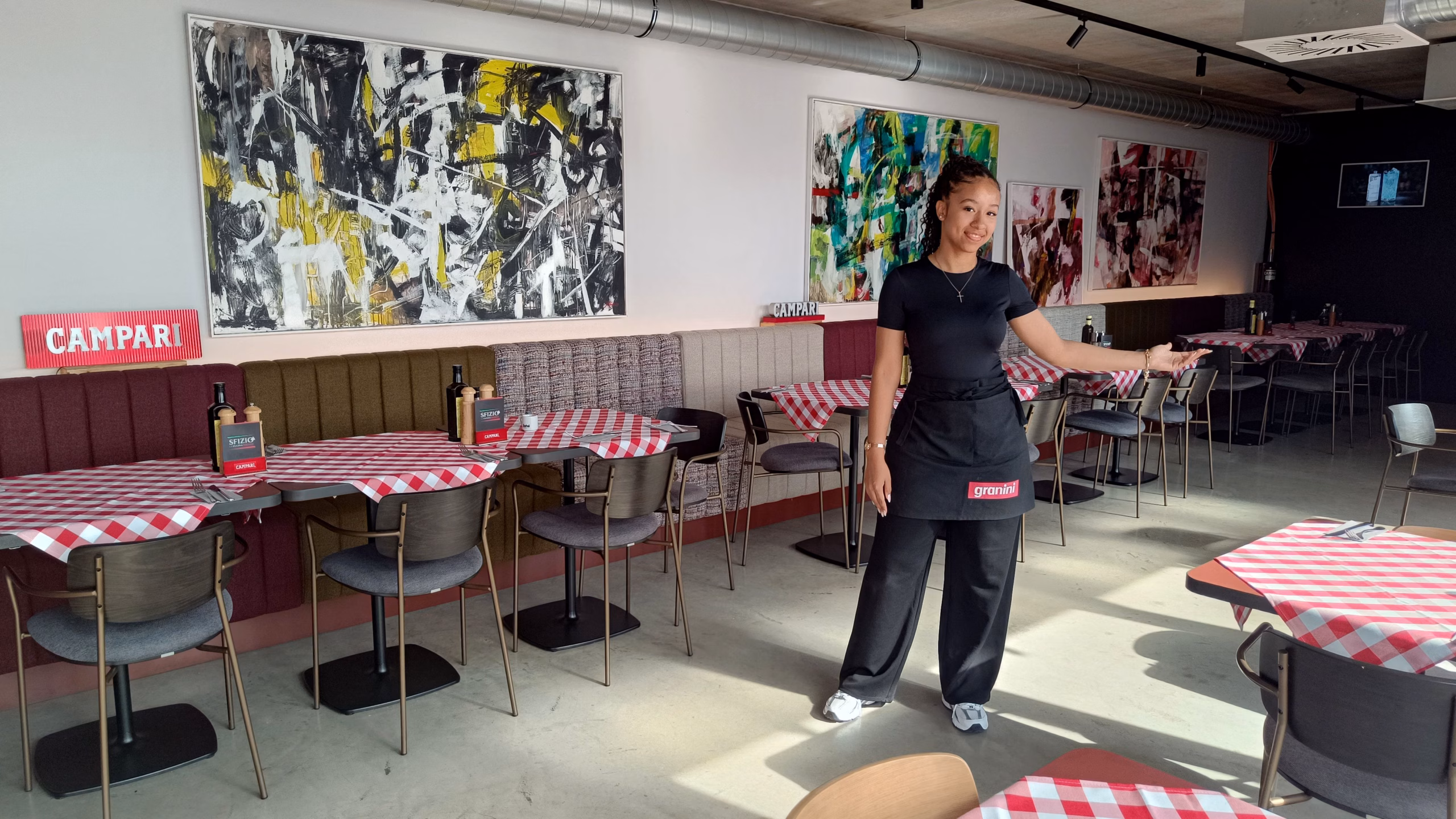 Mitarbeiterin Yara präsentiert: Die offene Architektur des Sfizio schafft Verbindung zum maritimen Außenbereich des Hafens.